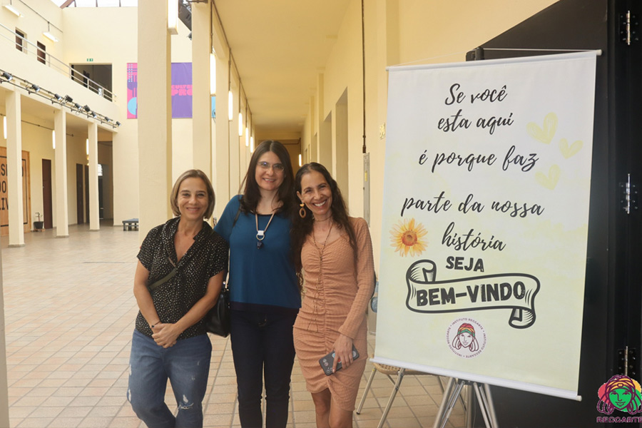 Cláudia Nascimento junto com Naná Roots do Instituto ReggArte ao lado de cartaz que diz: Se você está aqui é porque faz parte da nossa história. Seja bem-vindo.