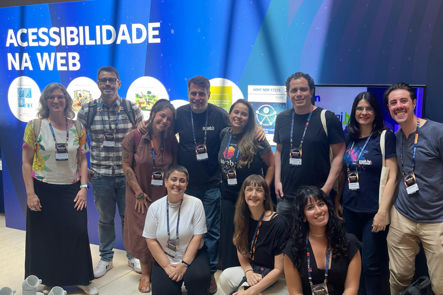 Grupo de especialistas e participantes em frente ao painel de Acessibilidade na Web