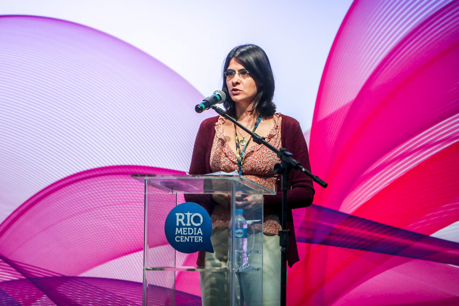 Cláudia Nascimento fala ao microfone em evento da premiação de acessibilidade.
