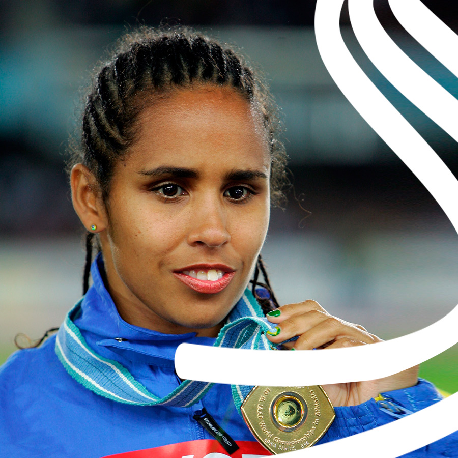 Foto de Adria Santos. Ela sorri, veste uniforme azul e segura uma medalha de ouro pendurada no pescoço.